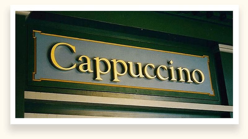 Gilded dimensional letters spelling Cappuccino on a storefront panel