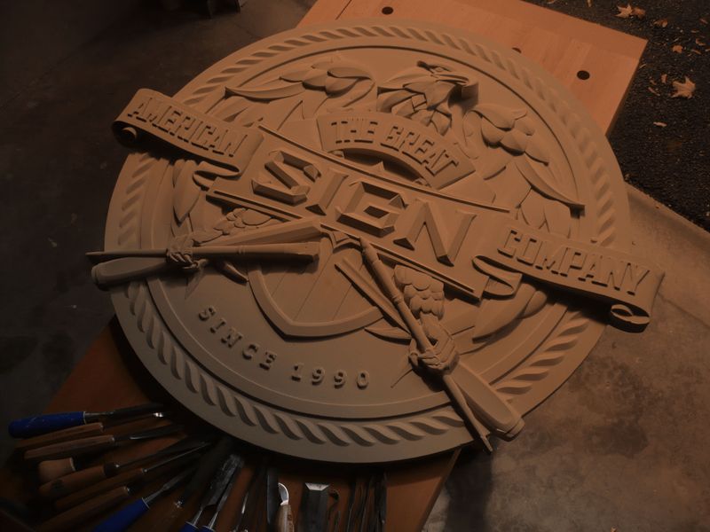 A carved crest on the bench beside the hand chisels used to cut it