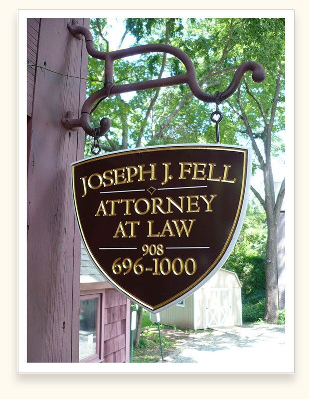Brown shield-shaped hanging sign with gold leaf lettering for attorney Joseph J. Fell