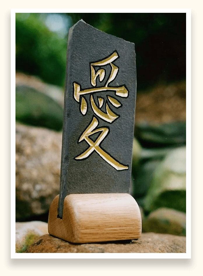 Slate stone carved with the Chinese character for love, gilded in gold, on a turned oak base