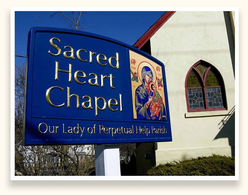 Blue sign with gold leaf lettering and a painted icon for Sacred Heart Chapel