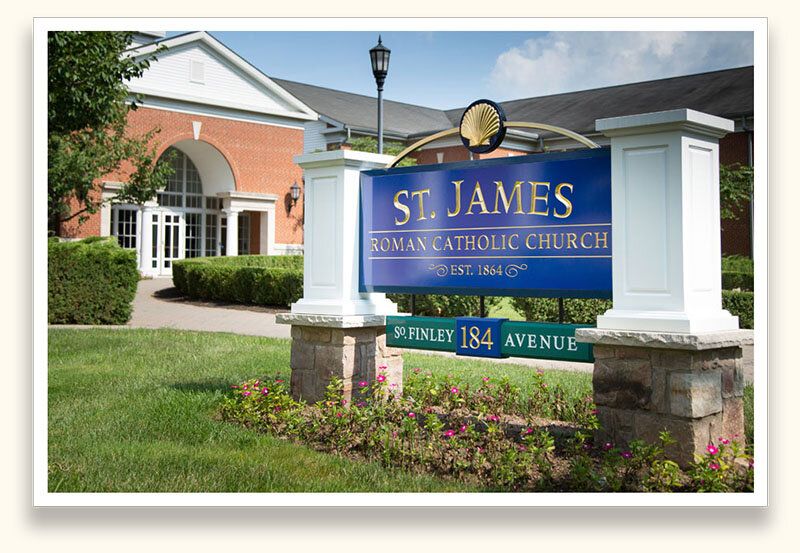 Blue and gold leaf monument sign for St. James Roman Catholic Church with a scallop shell emblem