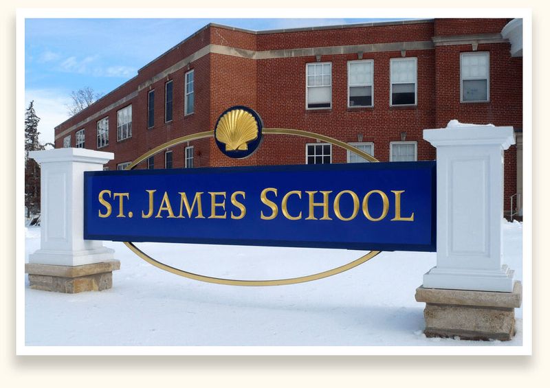 Navy sign with gold prismatic lettering and a gold ring for St. James School